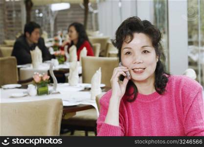 Mature woman sitting in a restaurant using a mobile phone