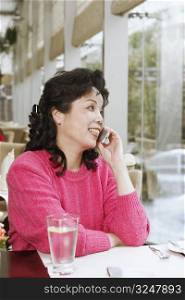 Mature woman sitting in a restaurant using a mobile phone