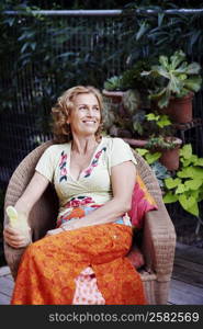 Mature woman sitting in an armchair and holding a glass of lemonade