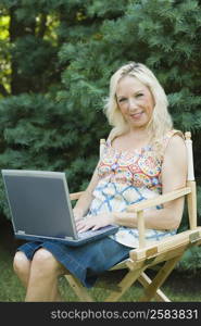 Mature woman sitting in an armchair and using a laptop