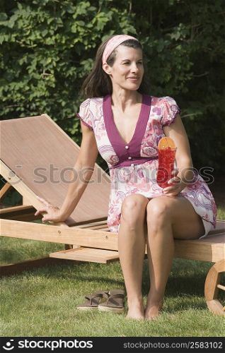 Mature woman sitting on a chaise lounge and smiling