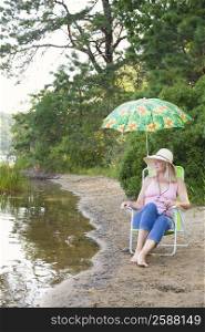 Mature woman sitting on a folding chair at the riverside