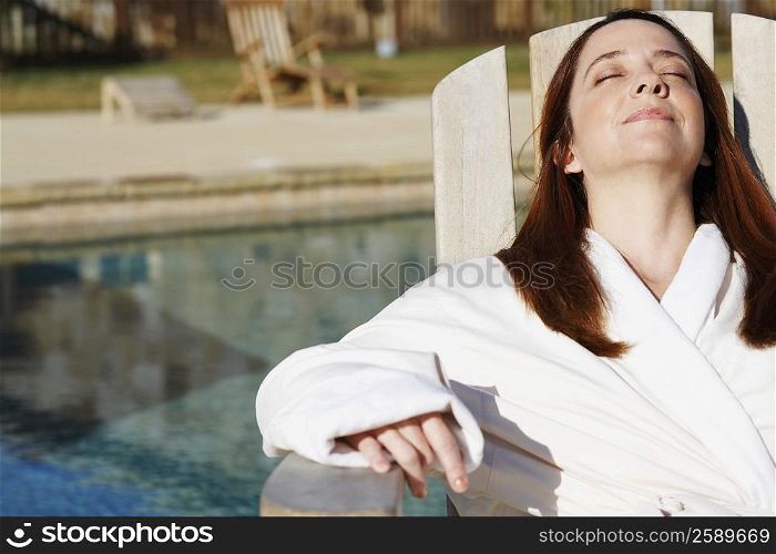 Mature woman sitting on a lounge chair with her eyes closed
