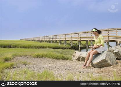 Mature woman sitting on a stone and reading a book