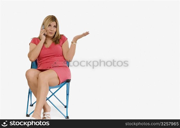 Mature woman sitting on a stool and talking on a mobile phone