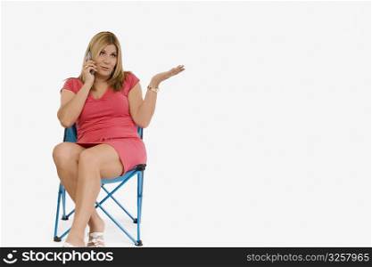 Mature woman sitting on a stool and talking on a mobile phone