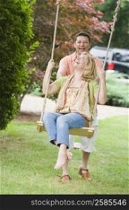Mature woman sitting on a swing and being pushed by a mature man