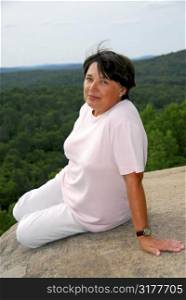 Mature woman sitting on scenic cliff edge