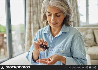 Mature Woman Sitting On Sofa At Home Taking Medication
