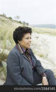 Mature woman sitting on the beach and smiling