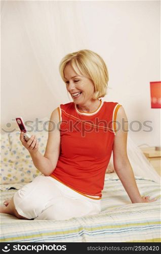 Mature woman sitting on the bed and holding a flip phone