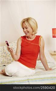Mature woman sitting on the bed and holding a flip phone
