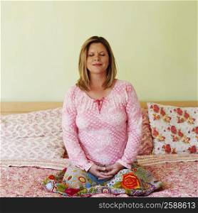 Mature woman sitting on the bed and meditating