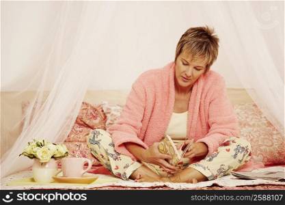 Mature woman sitting on the bed and reading a book