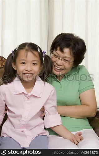 Mature woman sitting with her granddaughter and smiling
