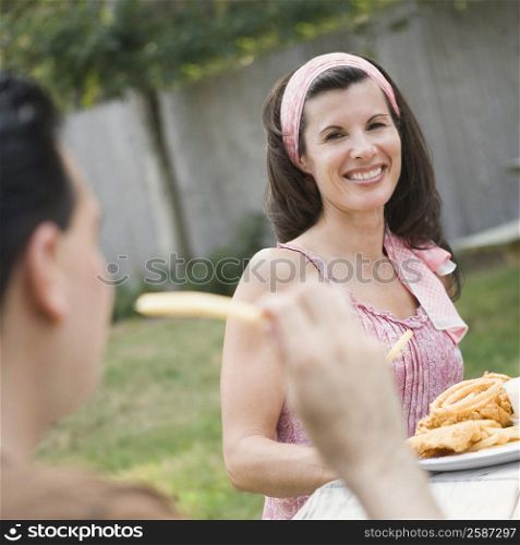 Mature woman smiling with a mature man eating snacks