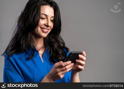 Mature woman sms texting, using app on smartphone. Pretty adult lady surfing internet with mobile phone. Grey studio portrait. Mature woman sms texting, using app on smartphone. Pretty adult lady surfing internet with mobile phone. Grey studio portrait.