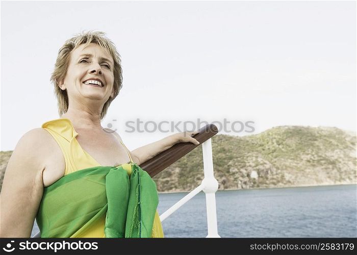 Mature woman standing at the railing of a sailing ship and smiling