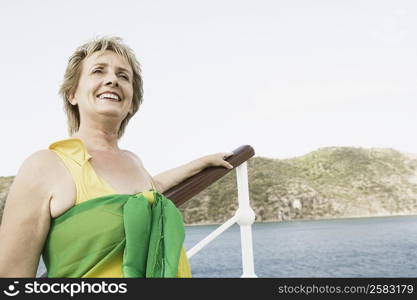 Mature woman standing at the railing of a sailing ship and smiling