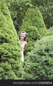 Mature woman standing behind a hedge and smiling