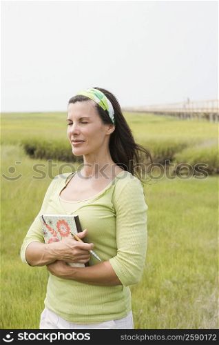 Mature woman standing in a field and holding a book