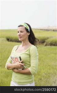 Mature woman standing in a field and holding a book
