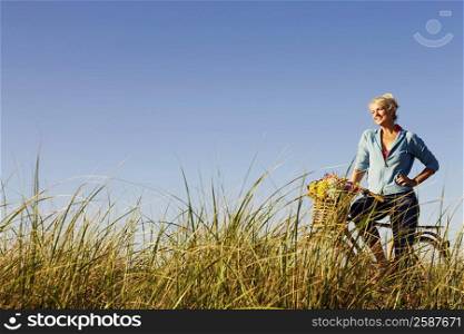 Mature woman standing in a field with a bicycle