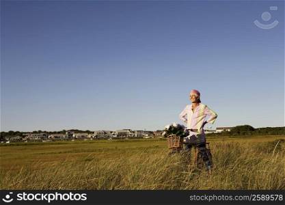 Mature woman standing in a field with a bicycle