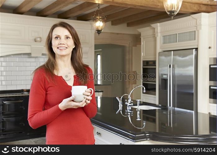 Mature Woman Standing In New Luxury Fitted Kitchen