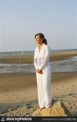 Mature woman standing on a rock on the beach
