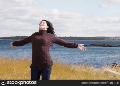 Mature woman standing on the beach with her arms outstretched