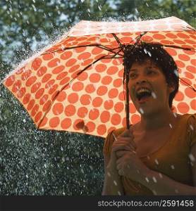 Mature woman standing under an umbrella in rain and shouting