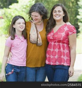 Mature woman standing with her two daughters and smiling
