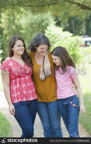 Mature woman standing with her two daughters and smiling