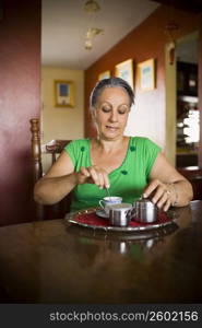 Mature woman stirring a cup of tea with a spoon