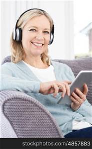 Mature Woman Streams Music From Digital Tablet To Wireless Headphones