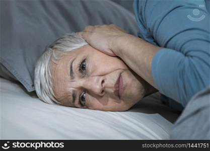 Mature woman suffering from Hyperacusis or Misophonia, lying in bed awake at Night. Sleeping Problems. Mature Woman Suffering From Hyperacusis or Misophonia