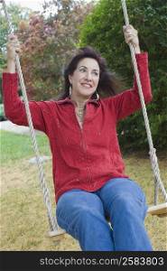 Mature woman swinging on a rope swing