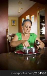 Mature woman taking a spoon of sugar from a container