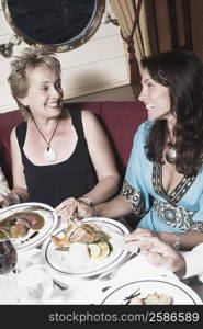 Mature woman taking food with a mid adult woman and smiling