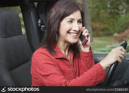 Mature woman talking on a mobile phone while driving a jeep