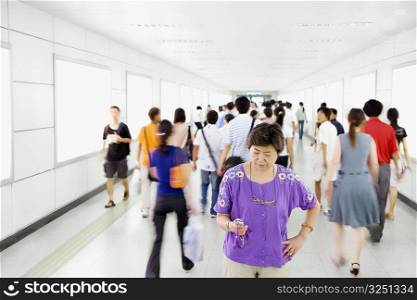 Mature woman text messaging on a mobile phone and standing in a corridor