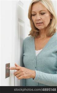 Mature Woman Turning Off Light Switch At Home