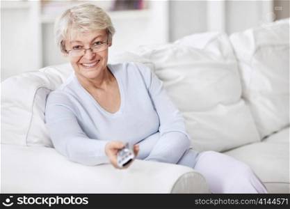 Mature woman TV remote control changes channels
