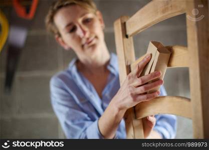 Mature Woman Upcycling Chair In Workshop At Home