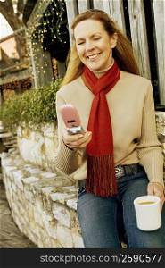 Mature woman using a mobile phone and holding a cup of tea