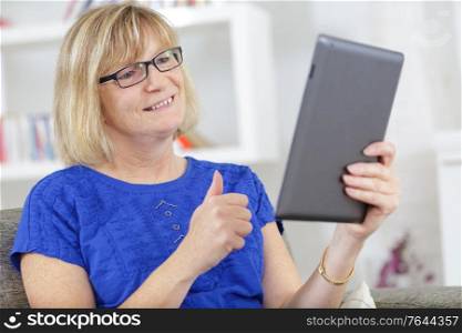mature woman using a tablet on the sofa