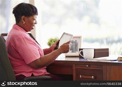 Mature Woman Using Digital Tablet On Desk At Home