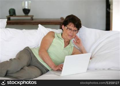 Mature woman using her laptop on a sofa