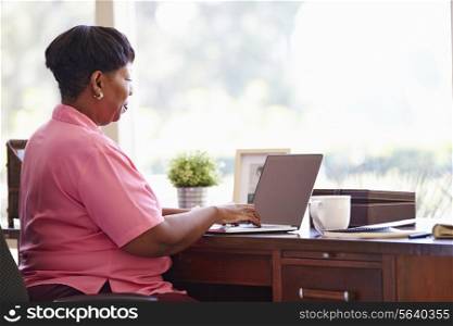 Mature Woman Using Laptop On Desk At Home